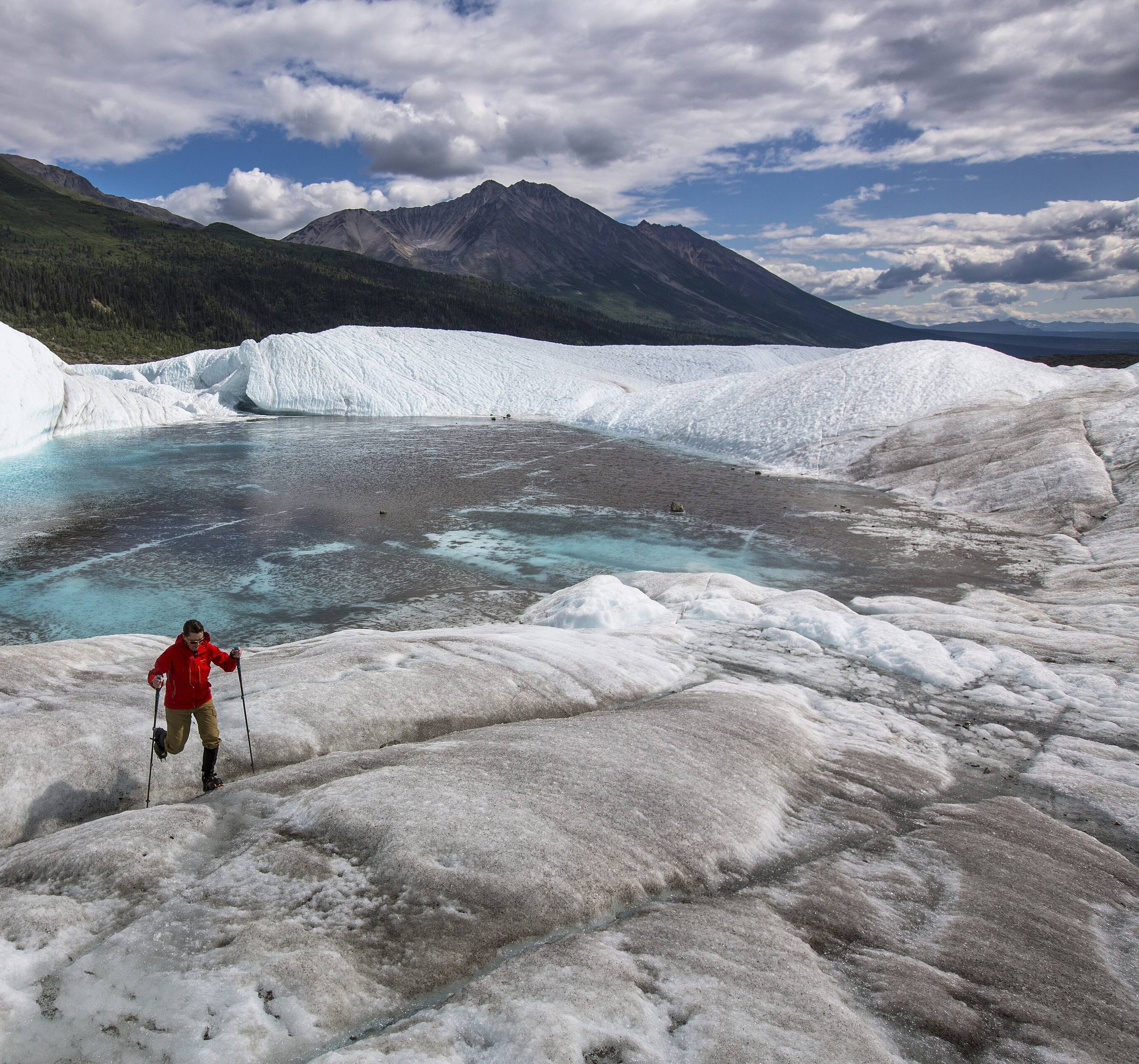 A lone hiker crossing crevassed glacier ice on the Root Glacier in Wrangell-St. Elias National Park, Alaska